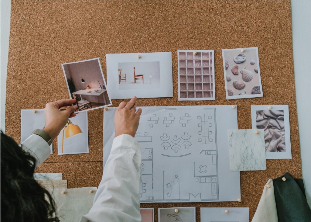 A person adding additional images to a corkboard.