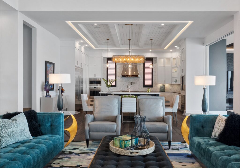 A living room with blue sofas, two leather chairs, and a coffee table with a view into the kitchen.