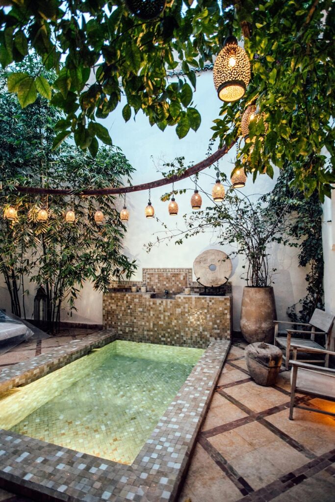 A tiled plunge pool with lanterns lights hanging above. 
